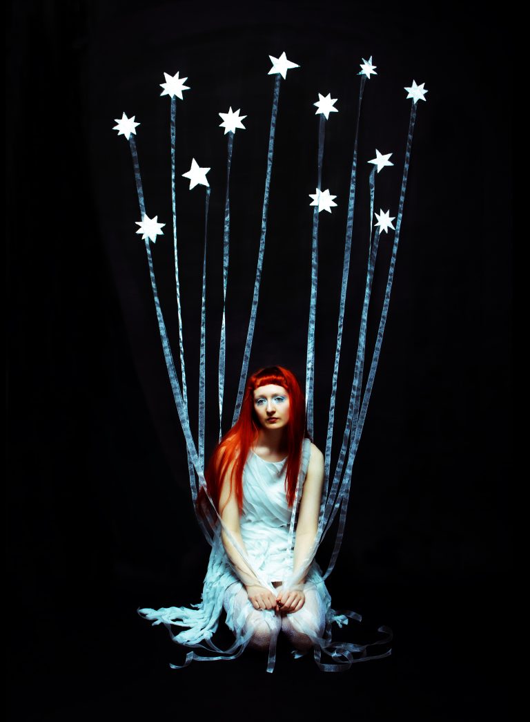 Photograph taken by Heidi Payne showing an ethereal human figure surrounded by the stars she's trying to pull from the sky.