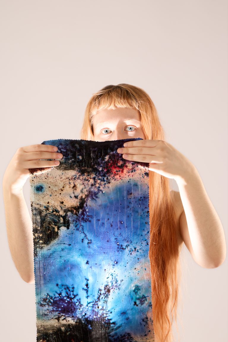 Model holding a blue experimental bio-leather textile with organic texture