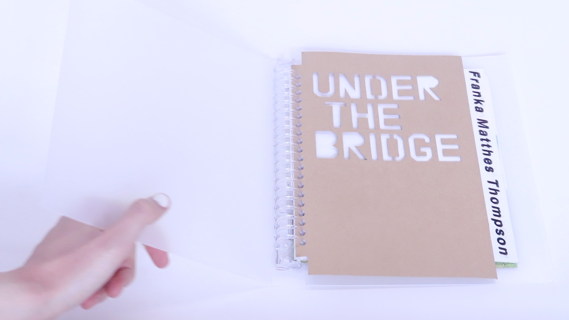 A video flipping through pages of a binder containing writing, drawings, and images