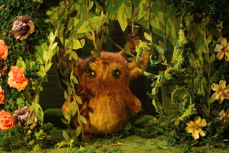 A felted puppet in a woodland setting