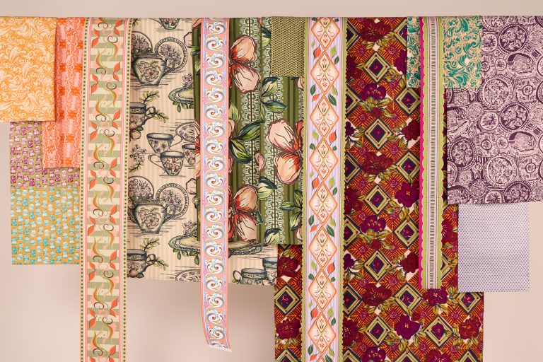 Collection of work by Jess Parker. A selection of hand printed textile fabrics hung on a rail photographed on a white background.